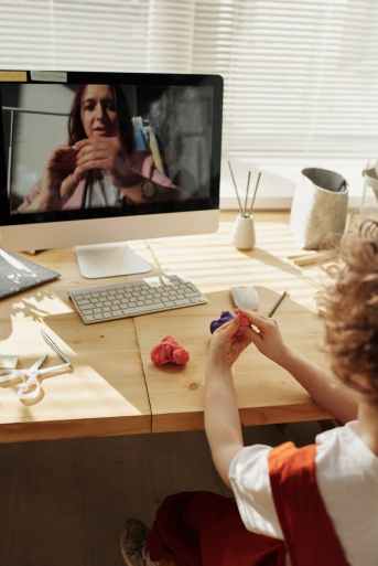 photo of kid playing with kinetic sand while watching through imac